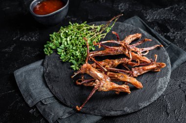 Cooked Spicy fried duck tongue. Black background. Top view.