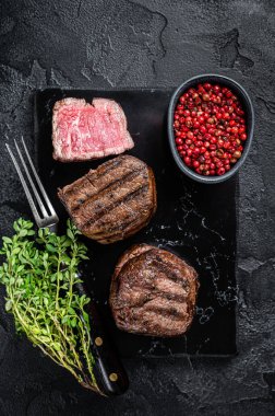 Grilled Fillet Mignon Steaks, dry aged beef tenderloin meat. Black background. Top view.