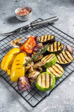 Seasonal summer Grilled vegetables on a grill, bell pepper, zucchini, eggplant, onion and tomato. Gray background. Top view.