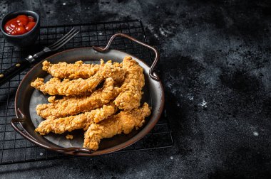 Crispy chicken tenders strips with Ketchup. Black background. Top view. Copy space.