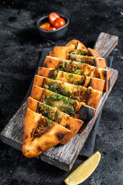 Sliced Turkish flatbread pide, Turkish pizza. Black background. Top view.