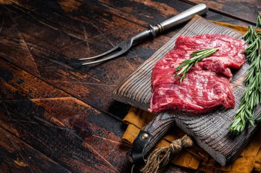 Raw alternative skirt beef steak on butcher board. Wooden background. Top view. Copy space.