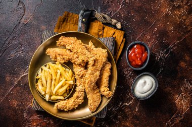 Dip fried Chicken breast strips with French Fries and sauces. Dark background. Top view.