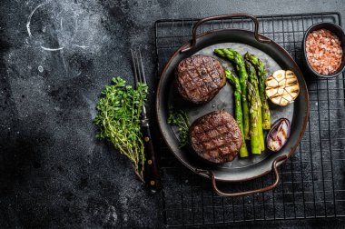 Grilled Fillet Mignon Steak with roasted asparagus. Black background. Top view. Copy space.