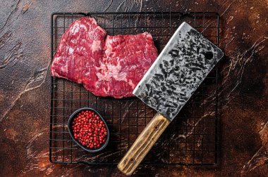 Raw skirt beef steak on meat cleaver. Black background. Top view.
