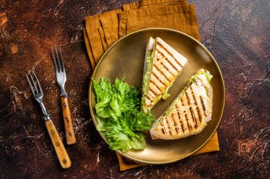 Sliced panini with ham, salad and cheese. Dark background. top view.