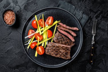 Grilled arrachera Skirt steak with garnish. Black background. Top view.