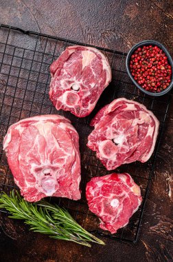Fresh Raw lamb neck meat slices, mutton meat on a rack with herbs. Dark background. Top view.