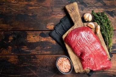 Alternative flank beef steak, raw meat. Wooden background. Top view. Copy space.