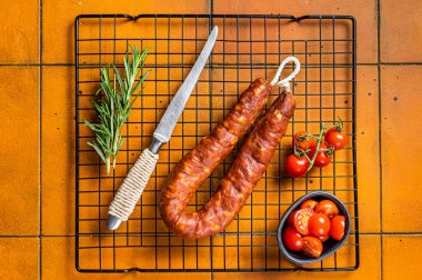 Spanish Chorizo sausage, dry cured pork with herbs and spices. Orange background. Top view.