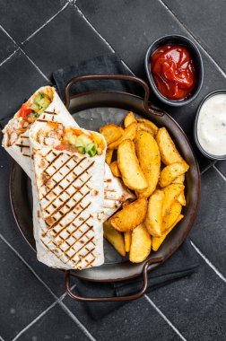 Shawarma Shaurma kebab with meat, vegetable salad and french fries. Black background. Top view.