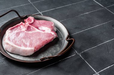Raw pork t bone chop meat steak. Black background. Top view. Copy space.
