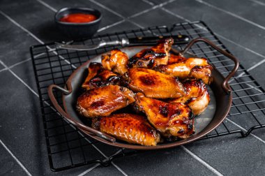 BBQ chicken wings in dip Barbecue sauce. Black background. Top view.