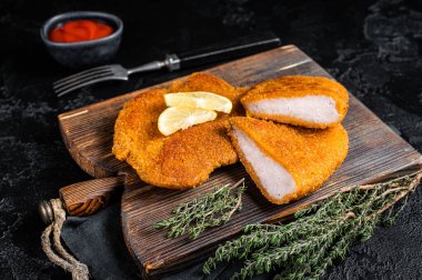 Viennese veal escalope, fried meat Schnitzel steak. Black background. Top view.