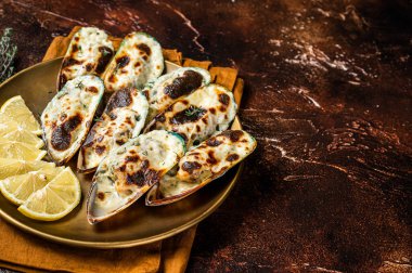 Baked large mussels with cheese, cilantro and lemon in shells. Dark background. Top view. Copy space.