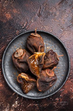 Dried persimmon fruit on a plate. Dark background. Top view.