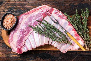 Raw lamb mutton ribs with herbs on wooden board. Wooden background. Top view.