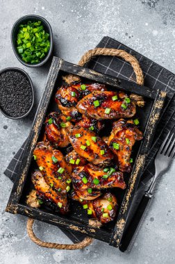 BBQ Chicken wings in Teriyaki sauce with black sesame in a tray. Gray background. Top view.