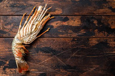 Fresh Spiny lobster on a wooden table, raw seafood. Wooden background. Top view. Copy space.
