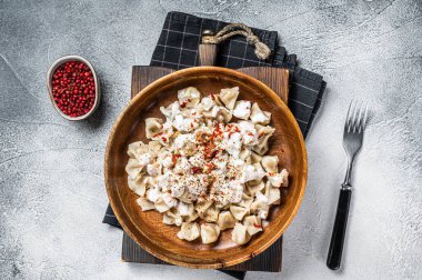 Manti Dumpling with yoghurt and tomato sauce in a wooden plate. White background. Top view.
