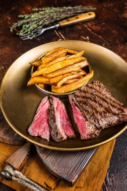 Elk steak with herbs and french fry, game meat. Dark background. Top view.