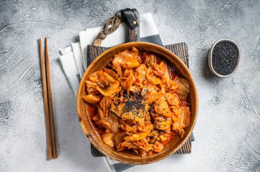 Kimchi cabbage in a wooden plate with chopsticks for eating , Korean cuisine. White background. Top view.