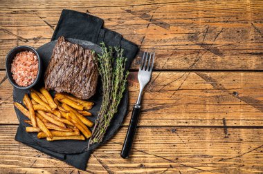 Venison dear steak with sea salt and french fry, game meat. Wooden background. Top view. Copy space.