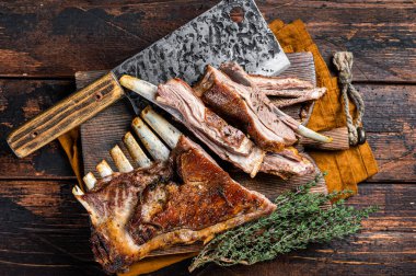 Roast lamb ribs, mutton spareribs, sliced meat on wooden board. Wooden background. Top view.