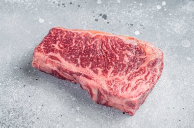 Raw Wagyu striploin or New york steak on a butcher table. Gray background. Top view.
