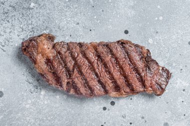 BBQ Grilled denver beef meat steak on a table. Gray background. Top view.