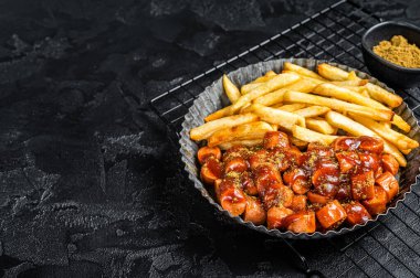 German fastfood currywurst meal, curry wurst with french fry. Black background. Top view. Copy space.