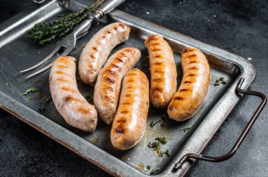 Grilled Bratwurst and Chorizo sausages on a steel serving tray. Black background. Top view.