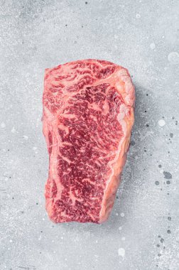 Raw Wagyu striploin or New york steak on a butcher table. Gray background. Top view.