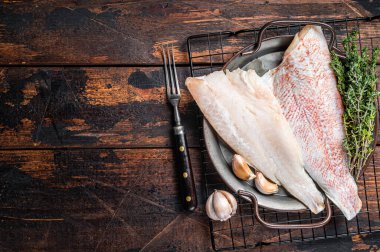 Raw red perch fillet, redfish fish meat in a steel tray. Wooden background. Top view. Copy space.