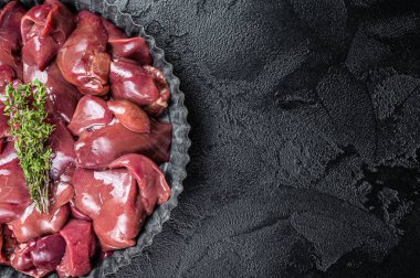 Uncooked Raw chicken liver, poultry offals in steel plate. Black background. Top view. Copy space.