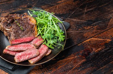 BBQ Grilled Wagyu New York beef meat steak or Striploin steak in a plate with salad. Wooden background. Top view. Copy space.