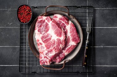 Raw pork cutlet chops for grill BBQ with pink pepper. Black background. Top view.