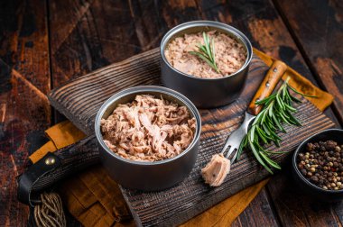 Can with Conserved tuna fillet meat. Wooden background. Top view.