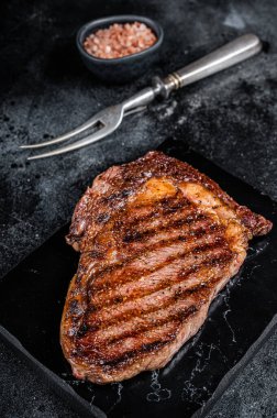 Grilled wagyu Rib Eye steak, marbled beef meat with salt. Black background. Top view.
