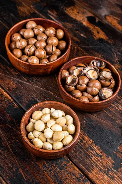 Unshelled Macadamia nuts ready to eat. Wooden background. Top view.
