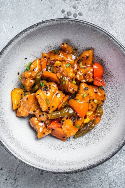 Chinese Sweet and Sour Pork guo bao rou in a bowl. Gray background. Top view.