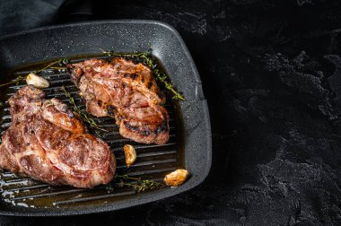 Grilled Pork steaks, neck meat on grill pan. Black background. Top view. Copy space.