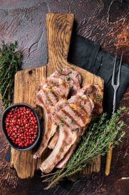 Grilled New Zealand Lamb Chops, mutton cutlets on wooden board. Dark background. Top view.