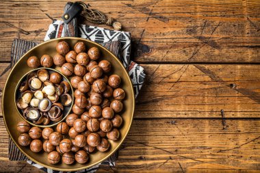 Organic Macadamia nuts in a shell ready to eat. Wooden background. Top view. Copy space.