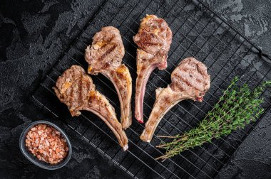 Barbecue Grilled lamb meat chops, mutton cutlets. Black background. Top view.