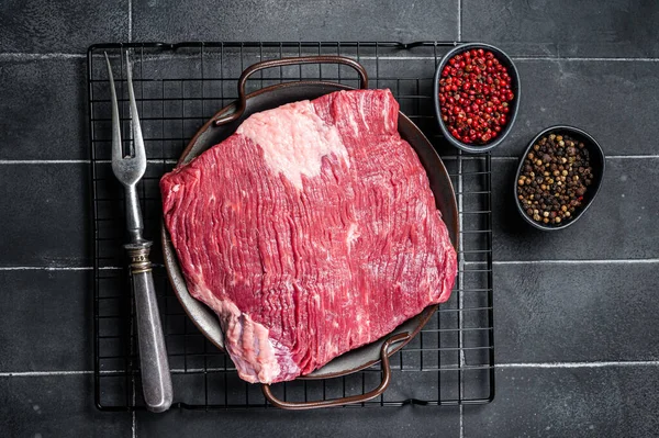Raw piece of marble beef brisket meat with spices. Black background. Top view.