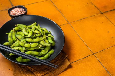 Deniz tuzu ve susam tohumlu haşlanmış Edamame Soya fasulyesi. Turuncu arka plan. Üst Manzara. Boşluğu kopyala.