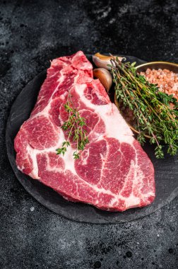 Pork loin steak, raw neck meat with thyme and salt. Black background. Top view.