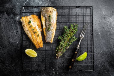 Grilled sea bass fillet with lime and thyme. Black background. Top view.