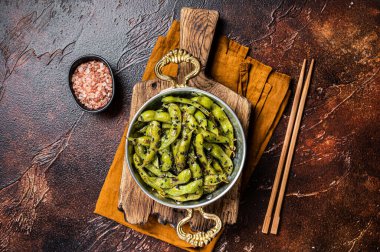Roasted green Edamame Soy Beans with sea salt and sesame seeds in a skillet. Dark background. Top view.